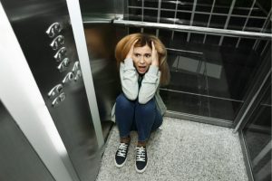 Miedo a los ascensores. Chica en ascensor con ataque de pánico.